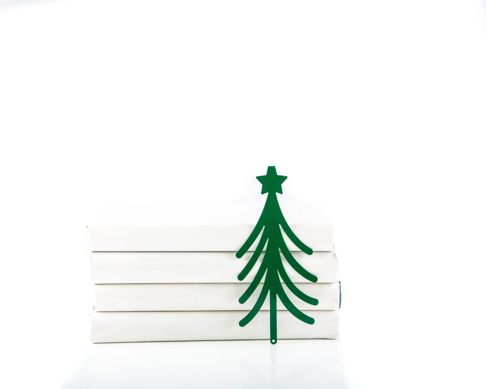 Christmas Tree metal bookmark in green lying on a stack of white books