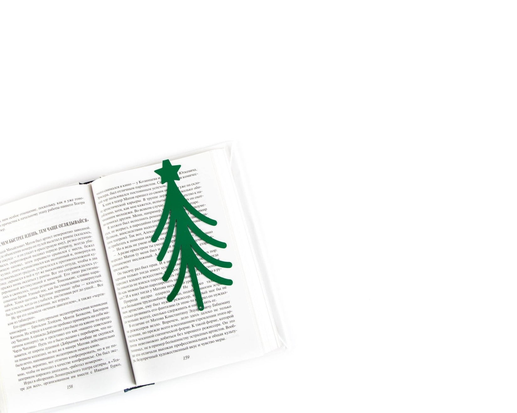 Christmas Tree metal bookmark in green lying across the pages of an open book