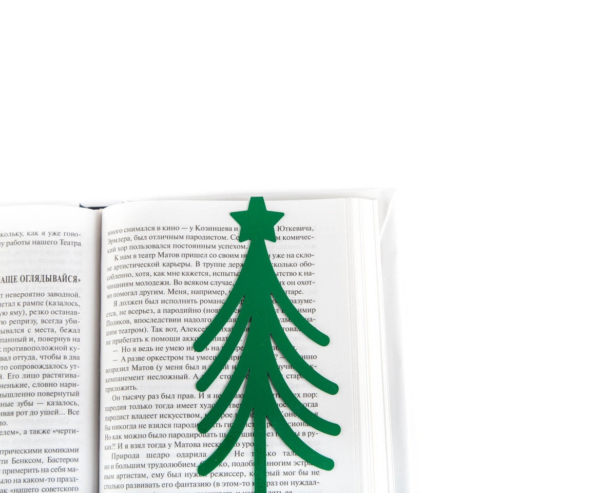 Christmas Tree metal bookmark in green resting on the pages of an open book