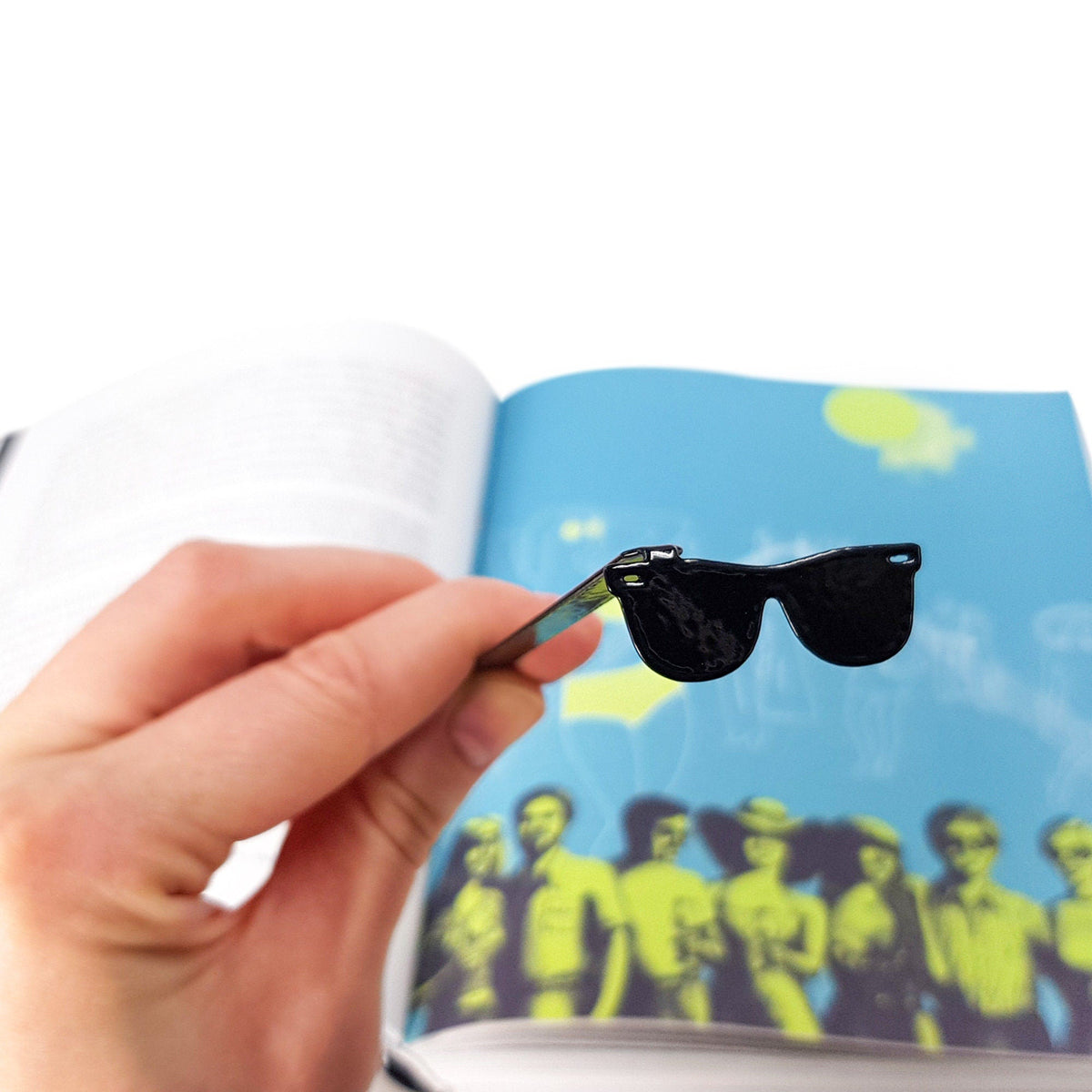 Cool Sunglasses metal bookmark held in a hand above an open book