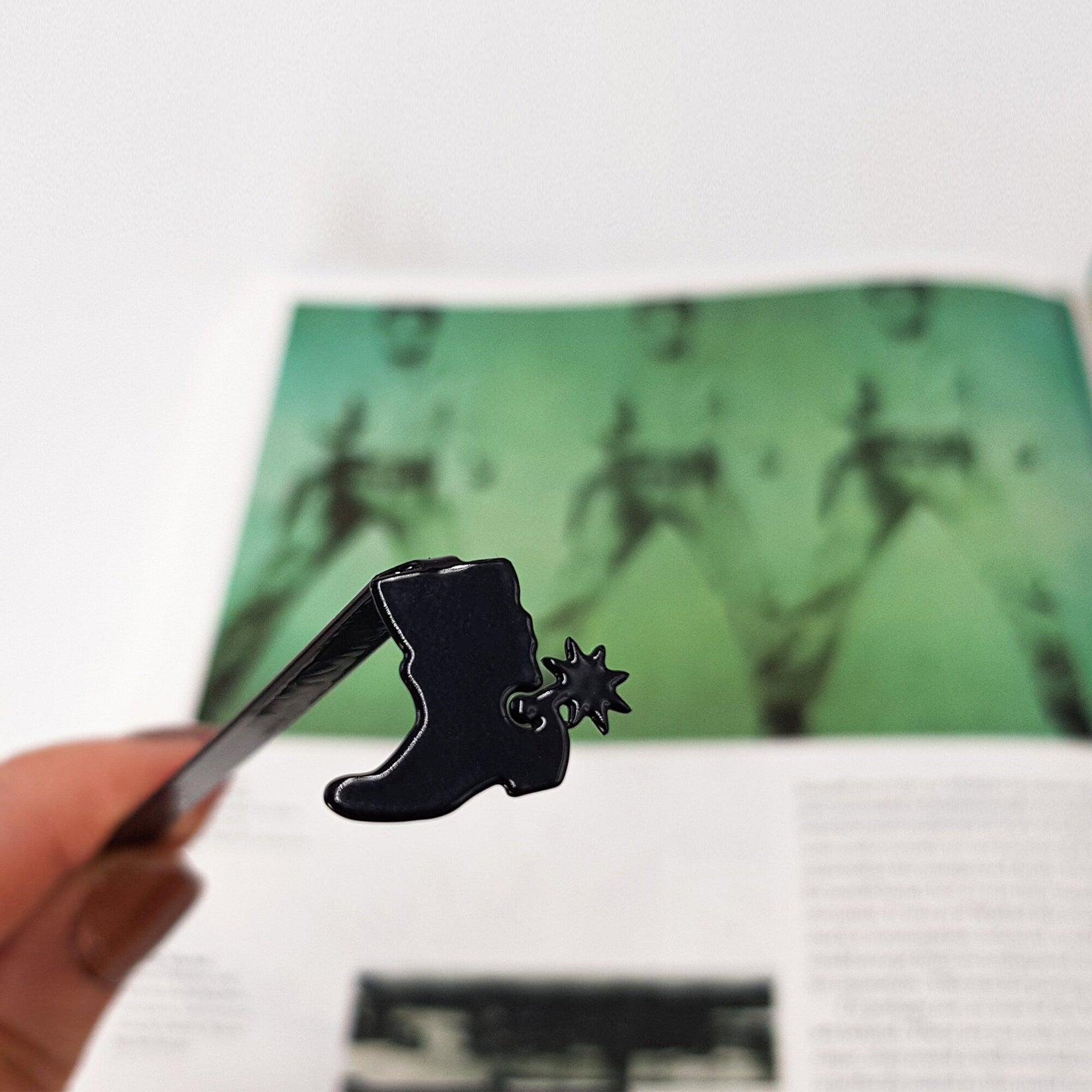 Cowboy's Boot metal bookmark marking a page in an illustrated book
