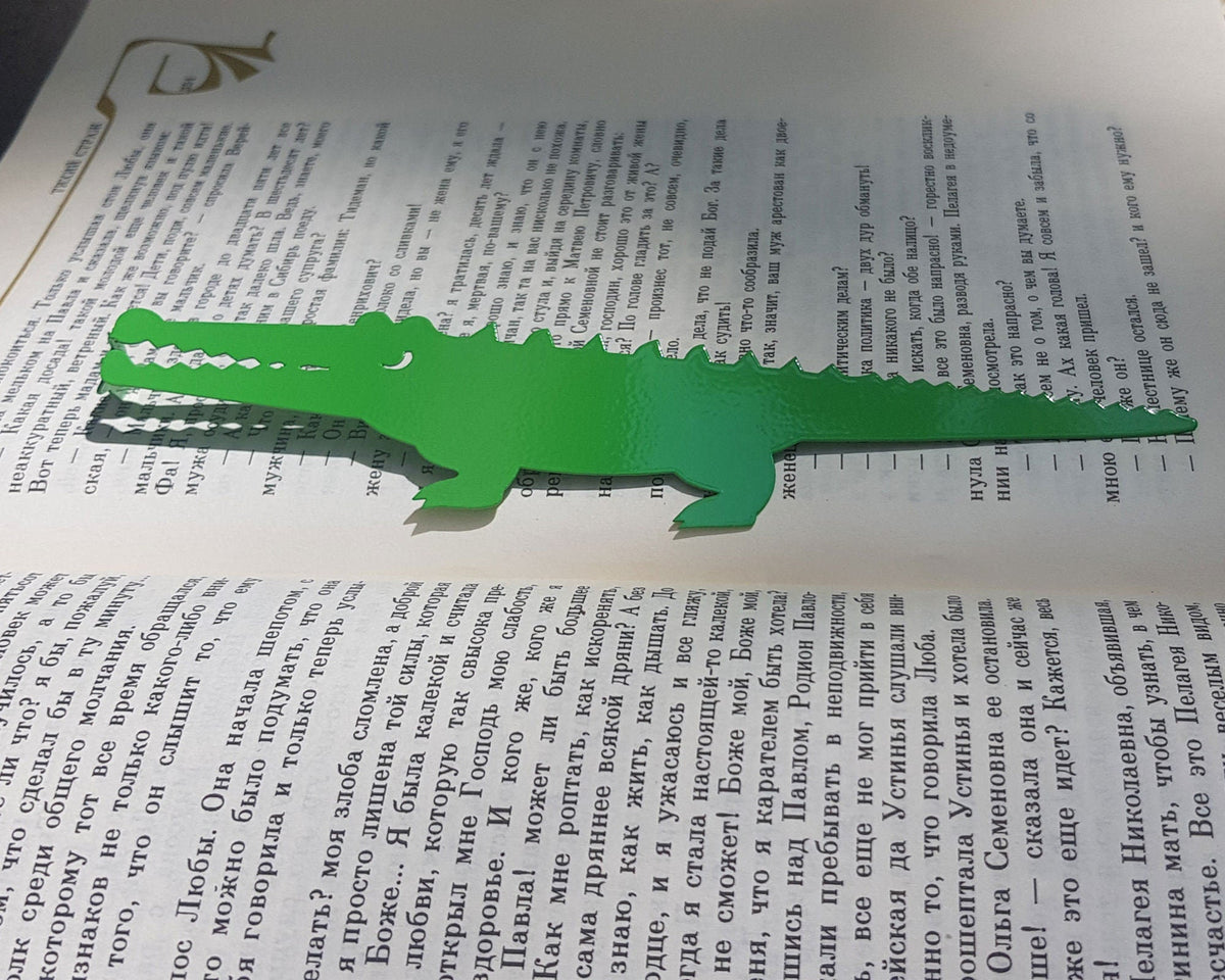 Crocodile and the Nile Bird metal bookmark in green resting on the pages of an open book
