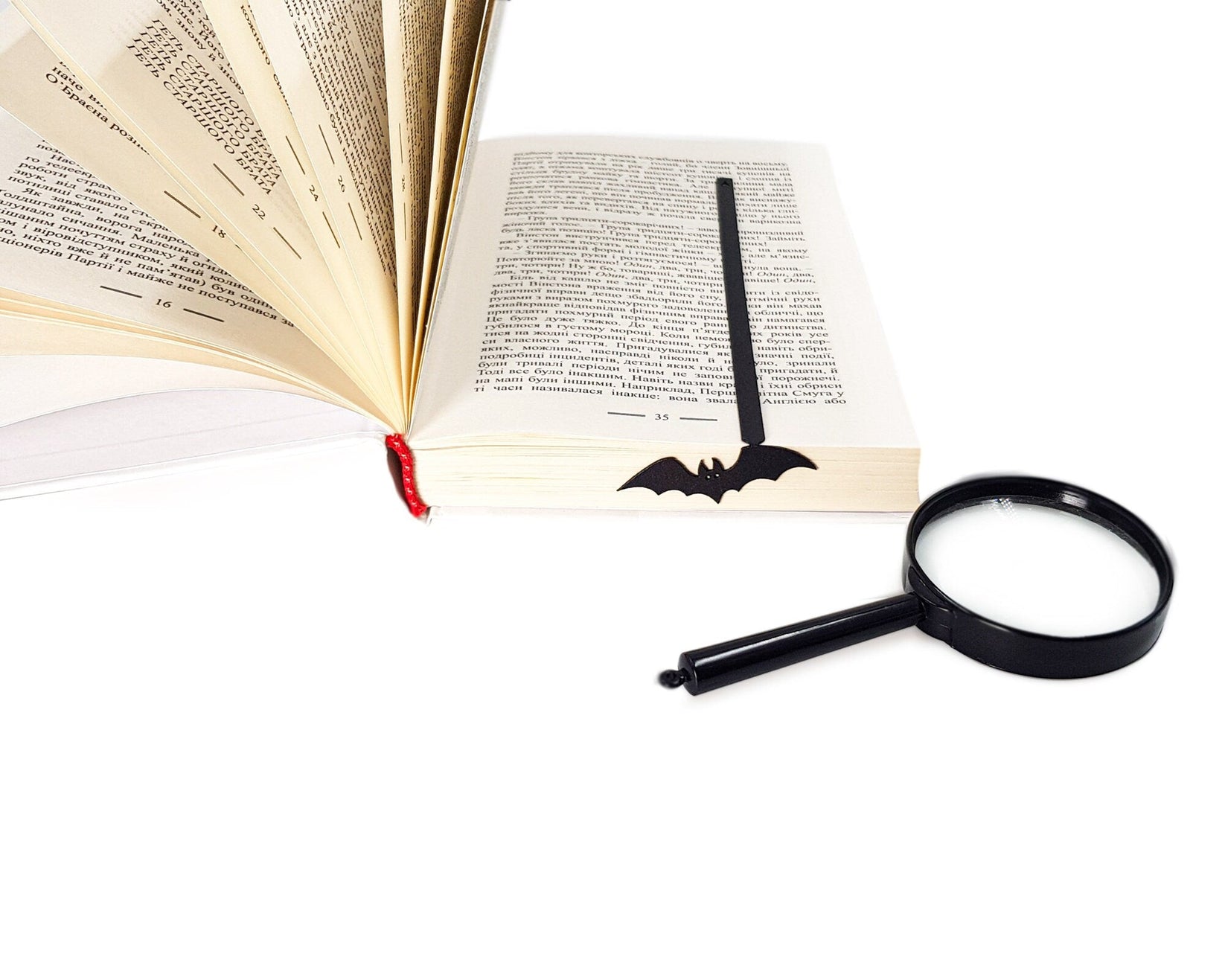 Cryptic Bat metal bookmark marking a page in an open book