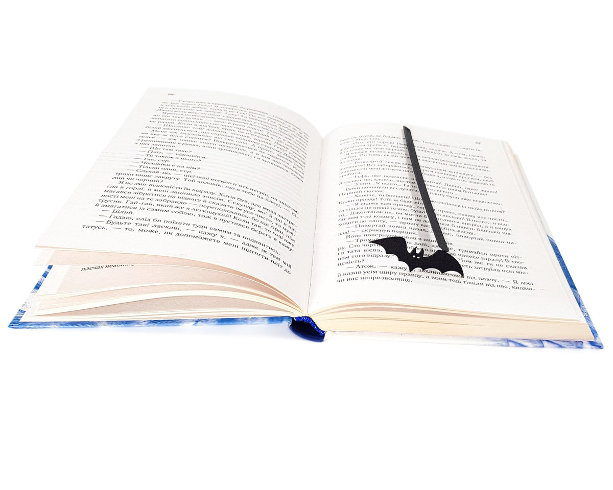 Cryptic Bat metal bookmark resting on the pages of an open book