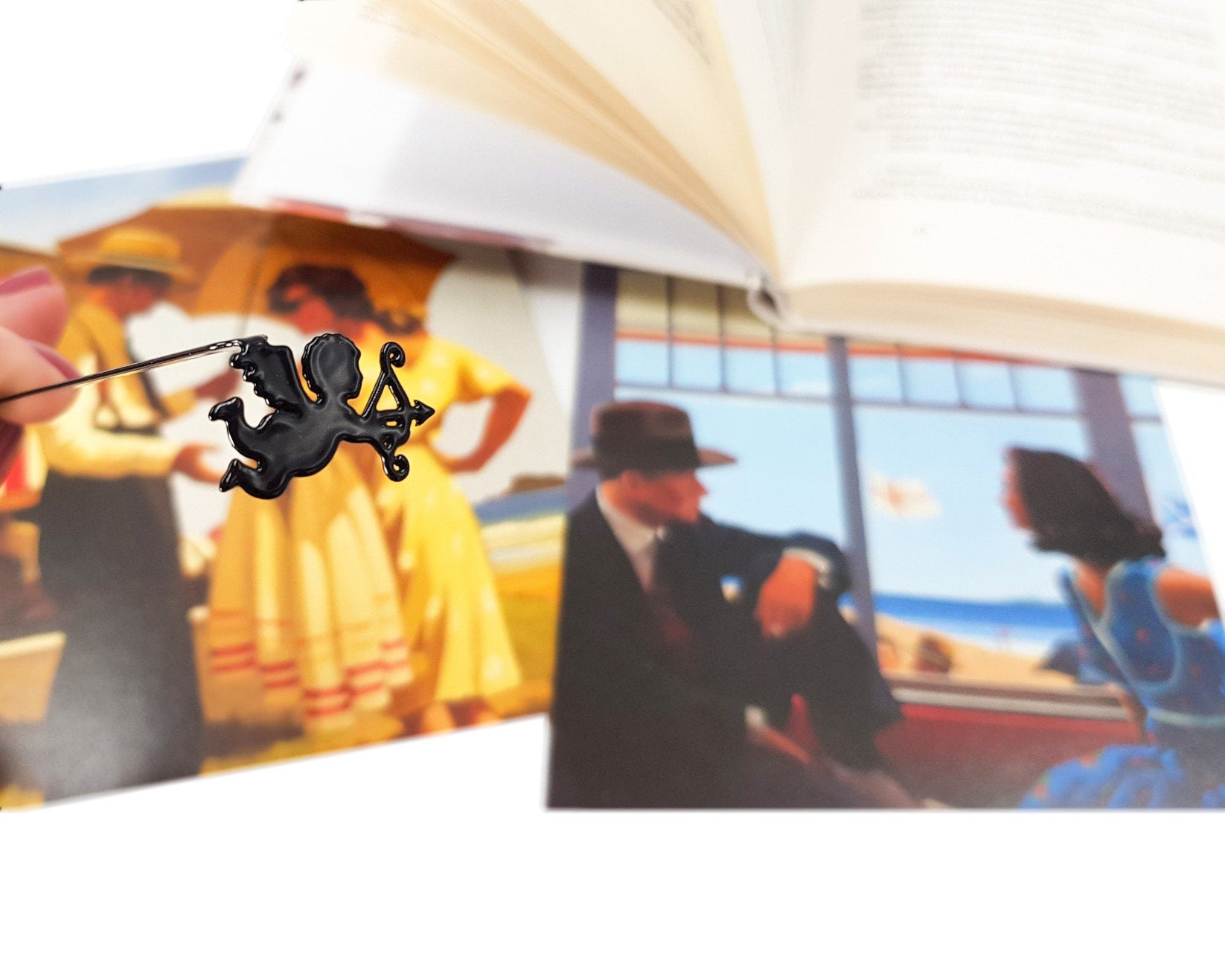 Cupid metal bookmark marking a page in an illustrated book