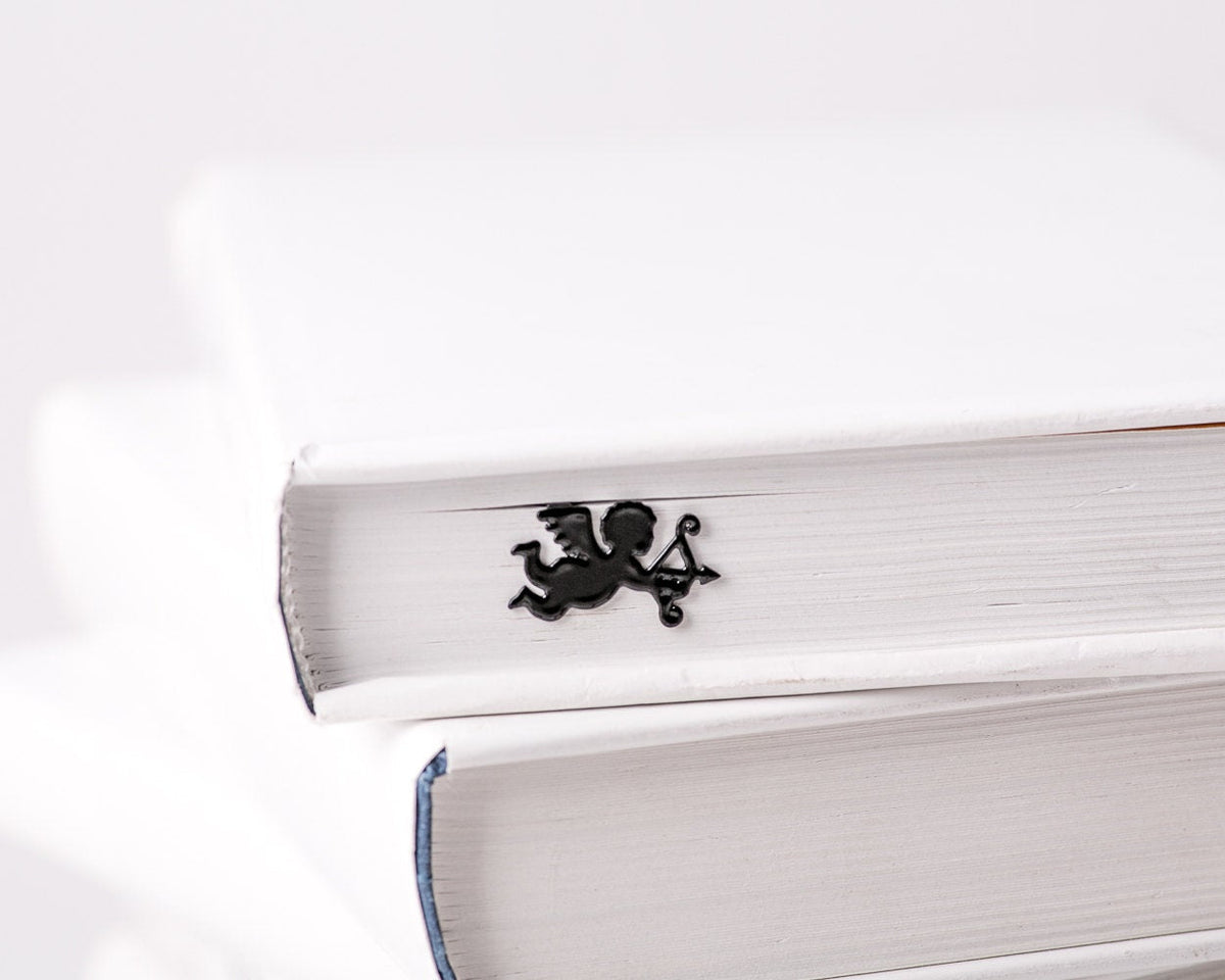 Cupid metal bookmark clipped in a closed book, viewed from the side
