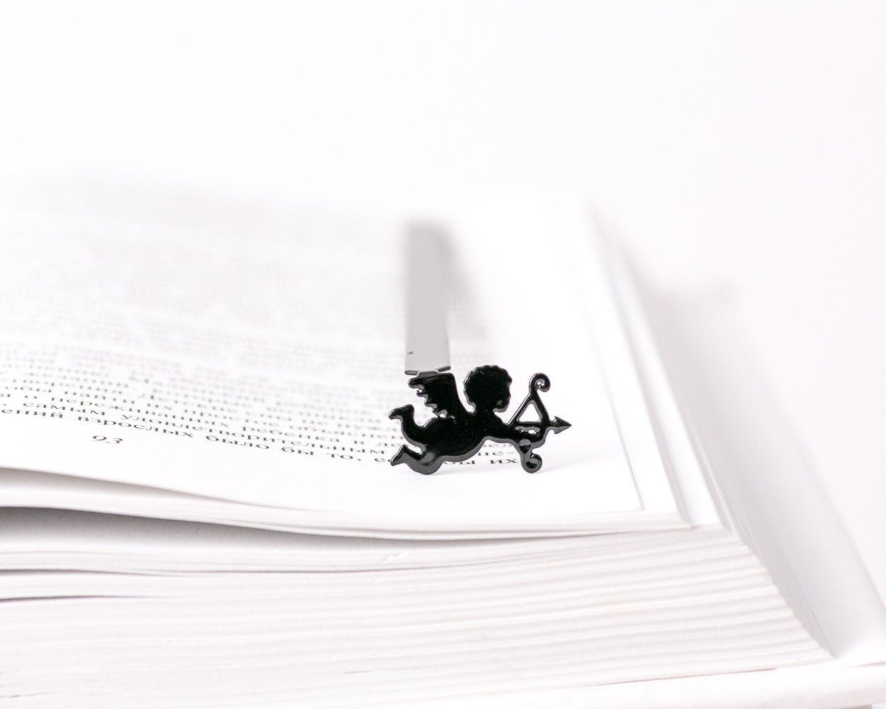 Cupid metal bookmark resting on the pages of an open book