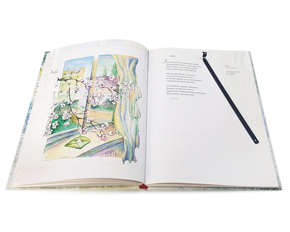 Curious Bird metal bookmark marking a page in an illustrated book, view 4