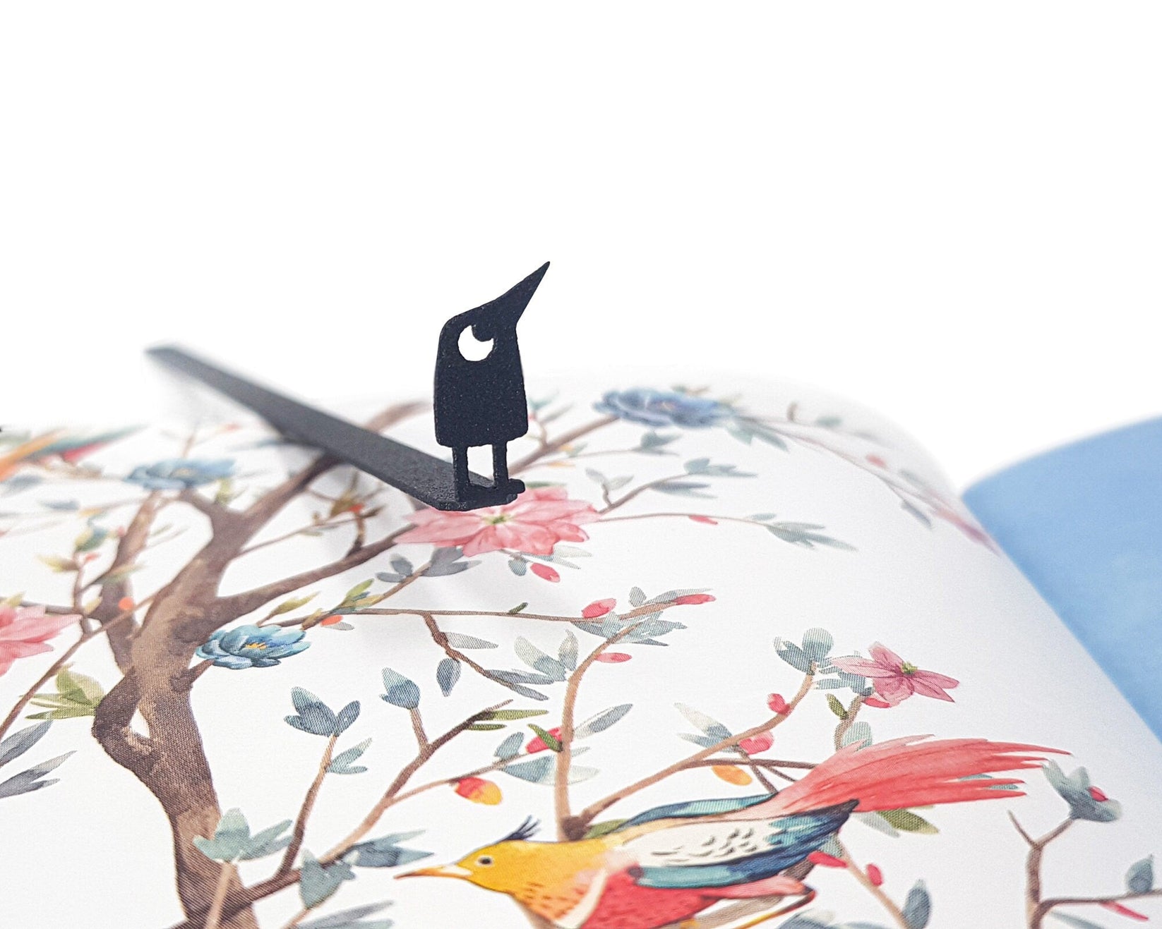 Curious Bird metal bookmark marking a page in an illustrated book