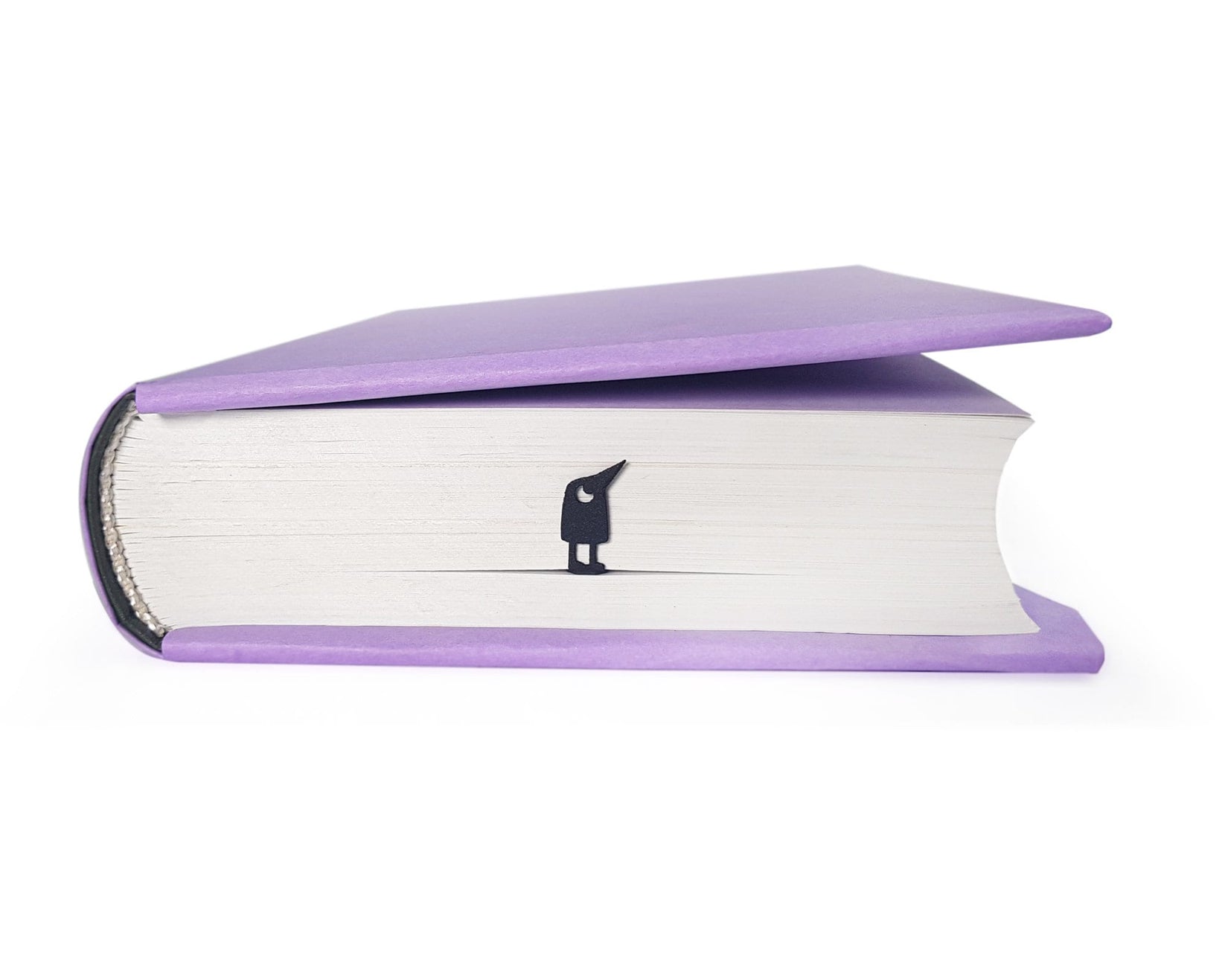 Curious Bird metal bookmark in a closed book, only its top showing above the pages