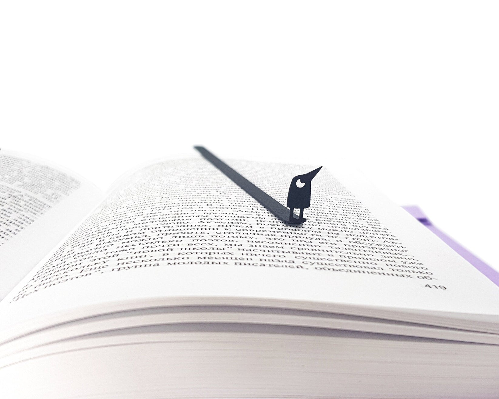 Curious Bird metal bookmark resting on the pages of an open book