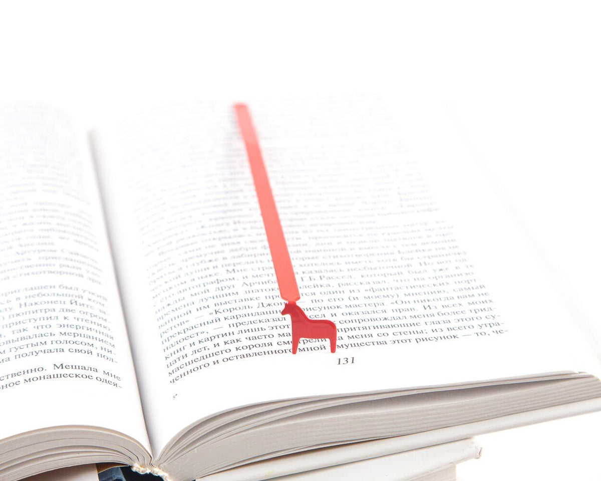 Dala Horse metal bookmark in red resting on the pages of an open book