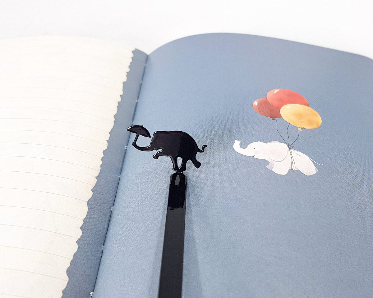 Dancing Elephant metal bookmark on an illustrated page