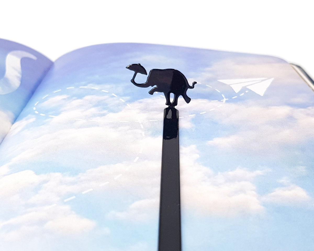 Dancing Elephant metal bookmark marking a page in an illustrated book