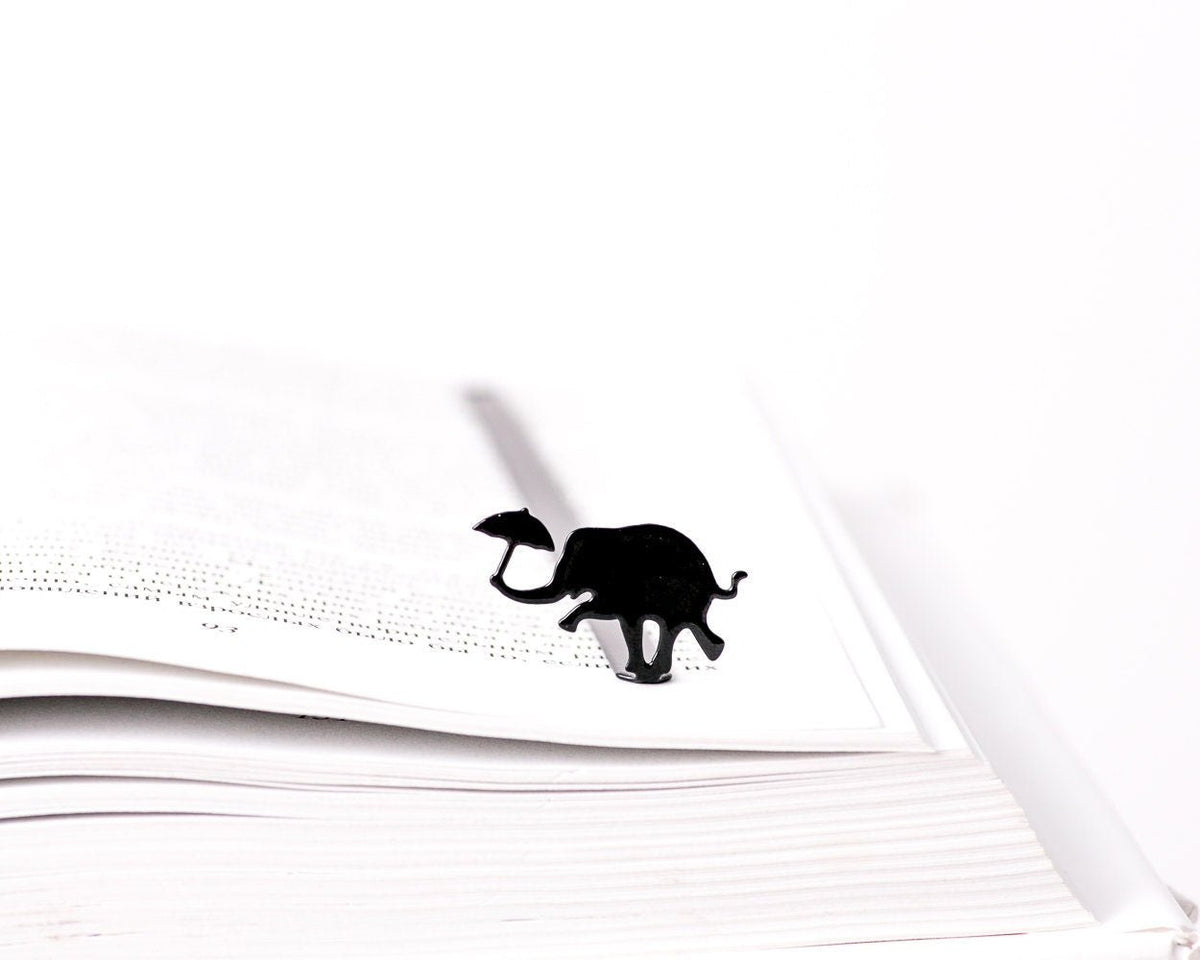 Dancing Elephant metal bookmark resting on the pages of an open book