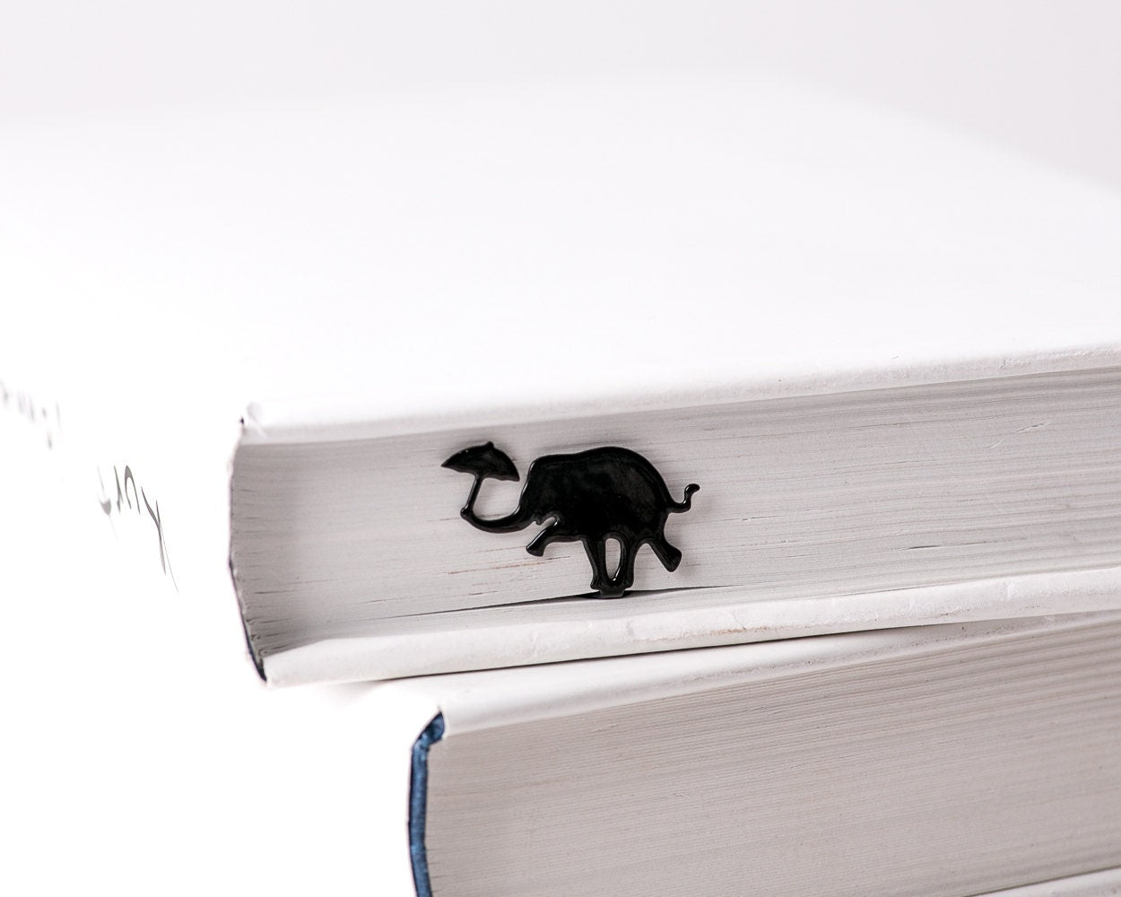 Dancing Elephant metal bookmark clipped in a closed book, viewed from the side