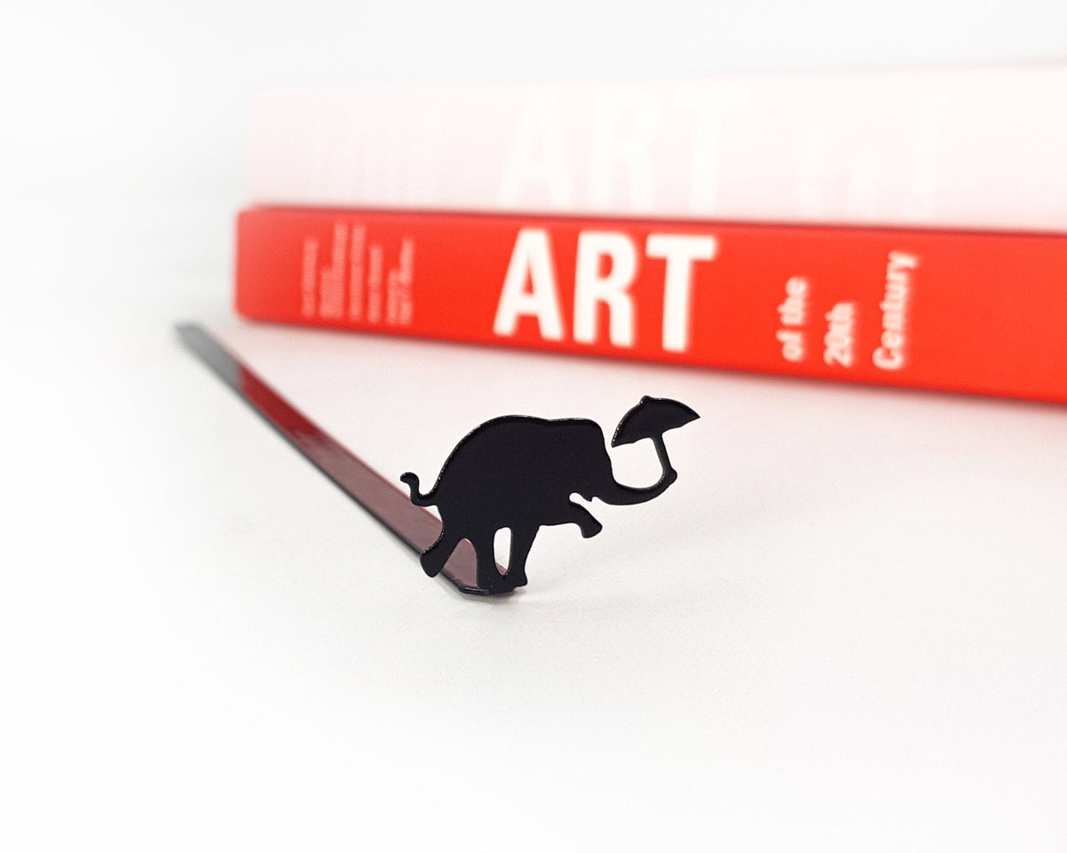 Dancing Elephant metal bookmark on a coloured background