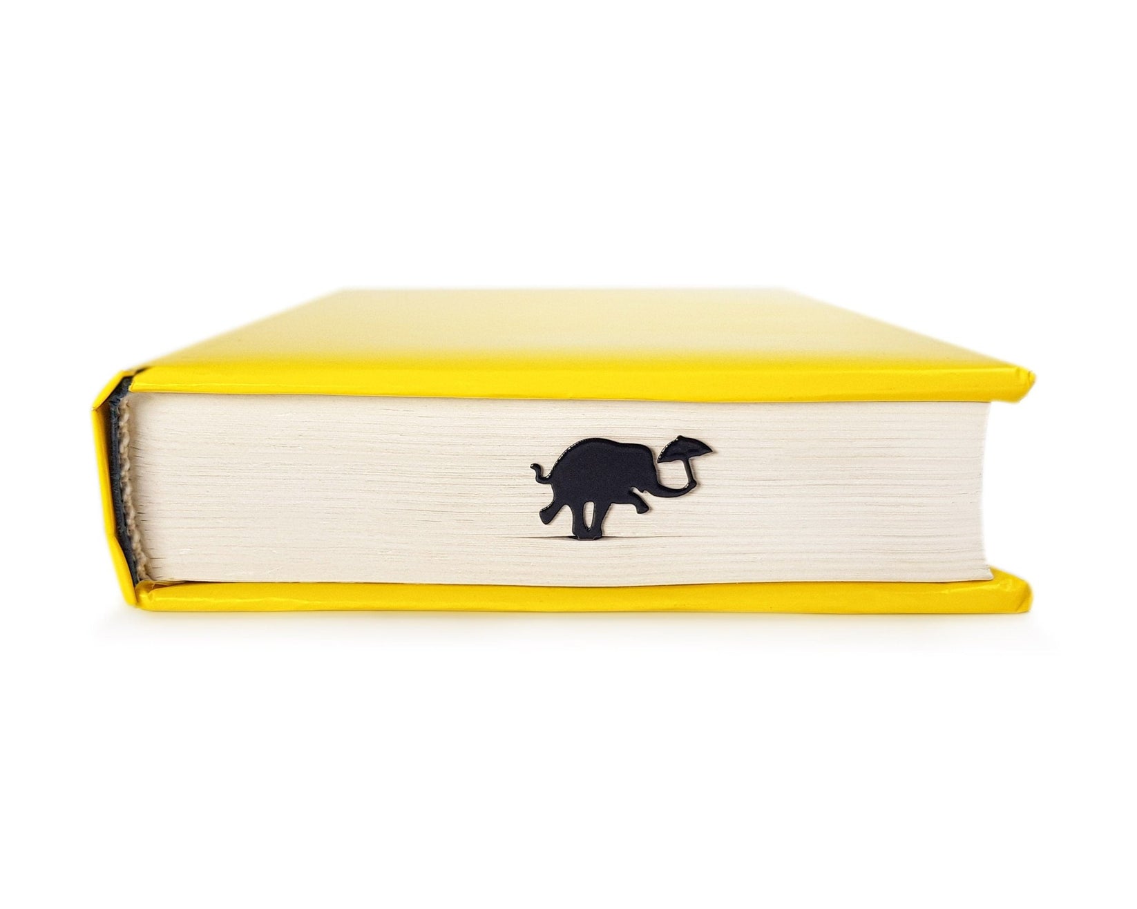 Dancing Elephant metal bookmark seen from the edge of a closed book