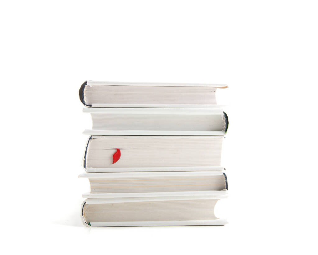 Devil's Trident metal bookmark in red shown with a stack of books