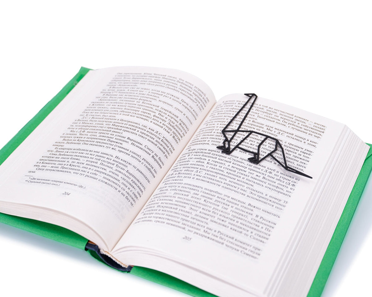 Dinosaur Geometry Style metal bookmark resting on the pages of an open book
