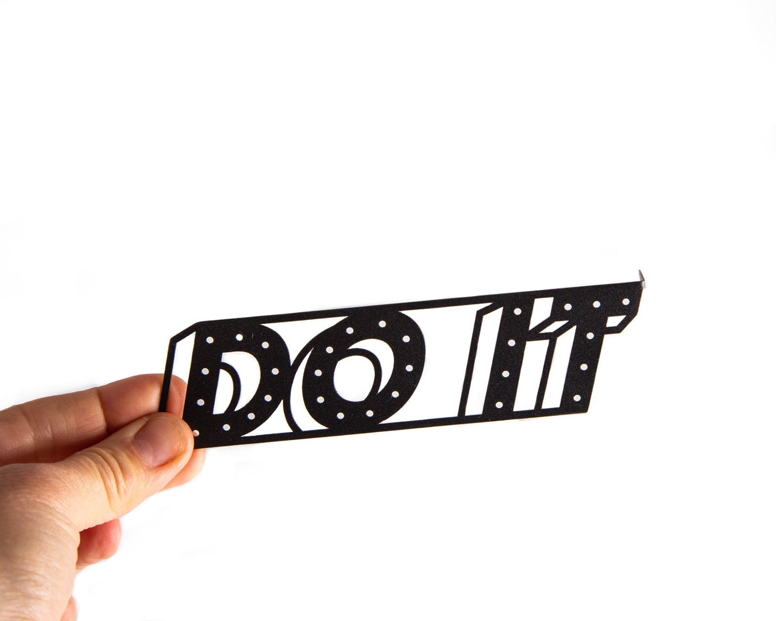 Do It metal bookmark held in a hand above an open book