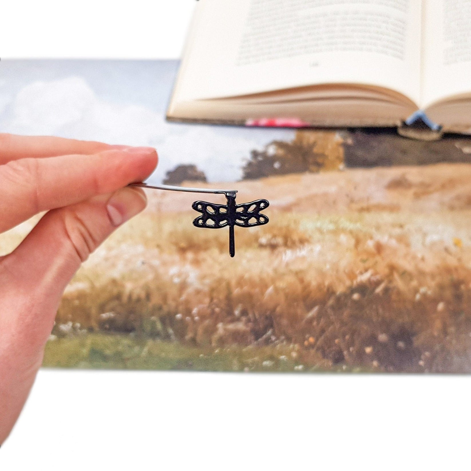 Dragonfly metal bookmark marking a page in an illustrated book