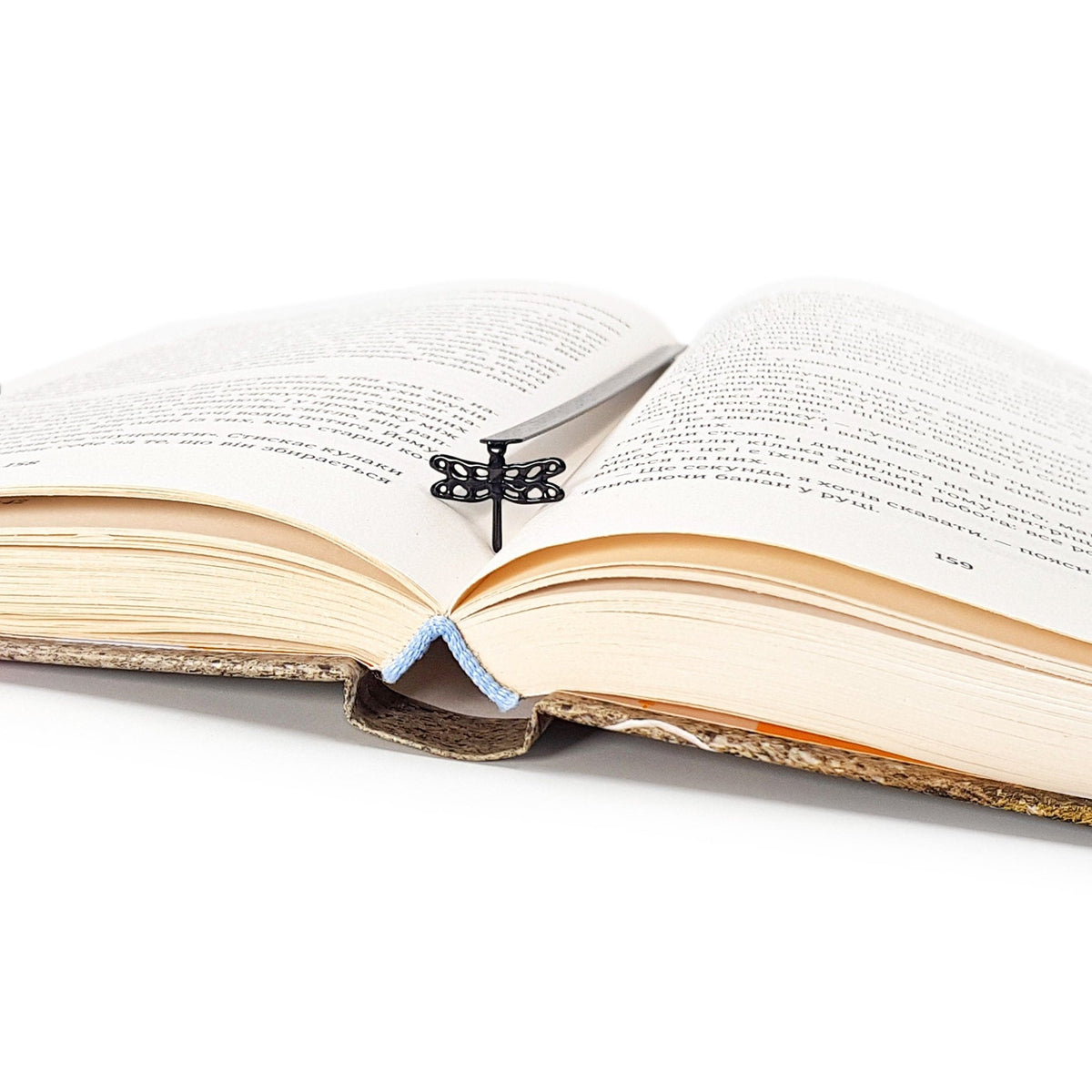 Dragonfly metal bookmark resting on the pages of an open book
