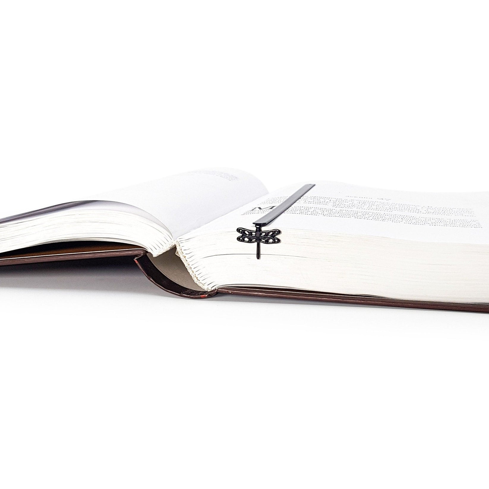 Dragonfly metal bookmark marking a page in an open book