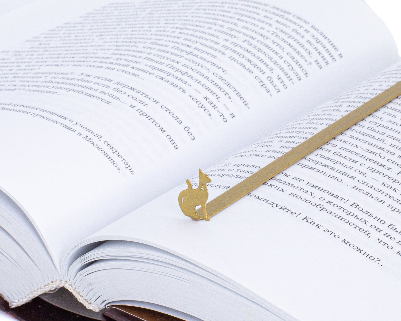 Egyptian Cat metal bookmark in gold resting on the pages of an open book
