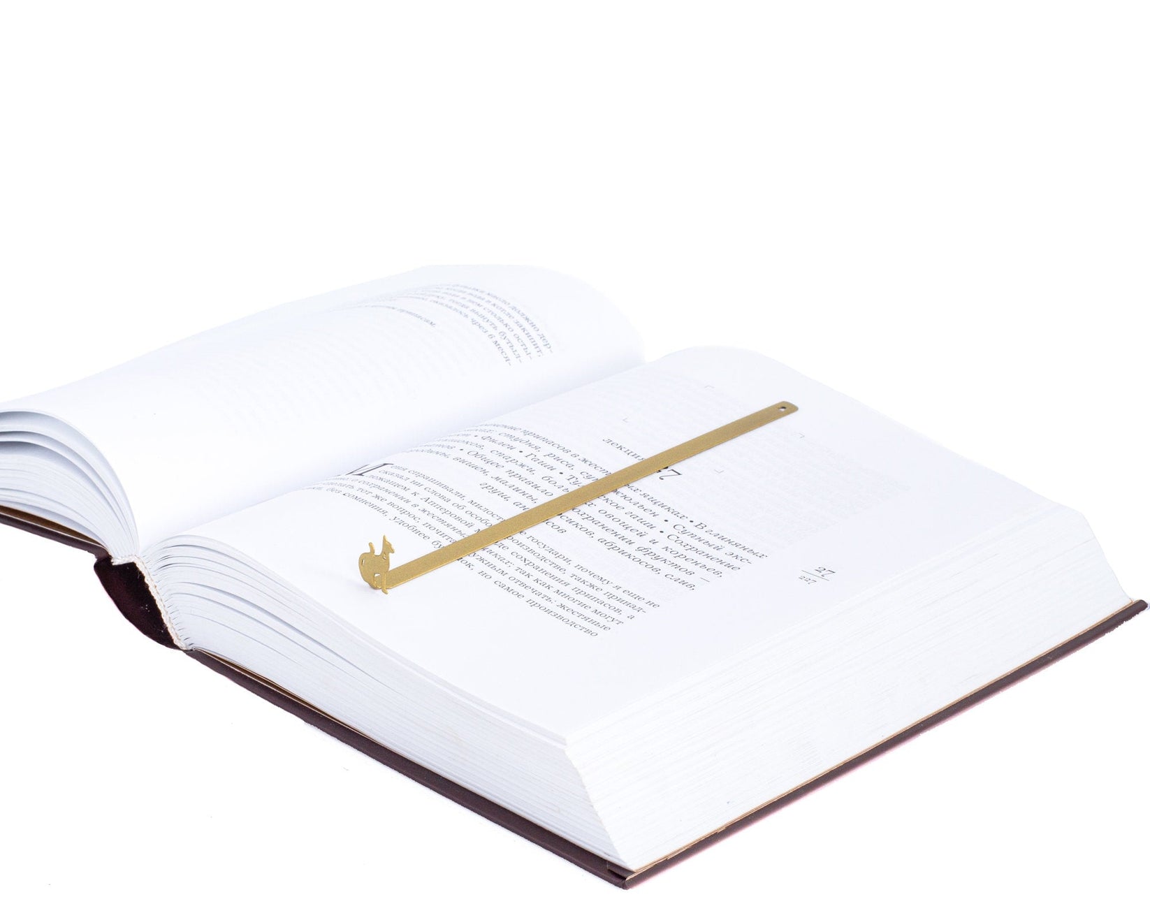 Egyptian Cat metal bookmark in gold lying across the pages of an open book