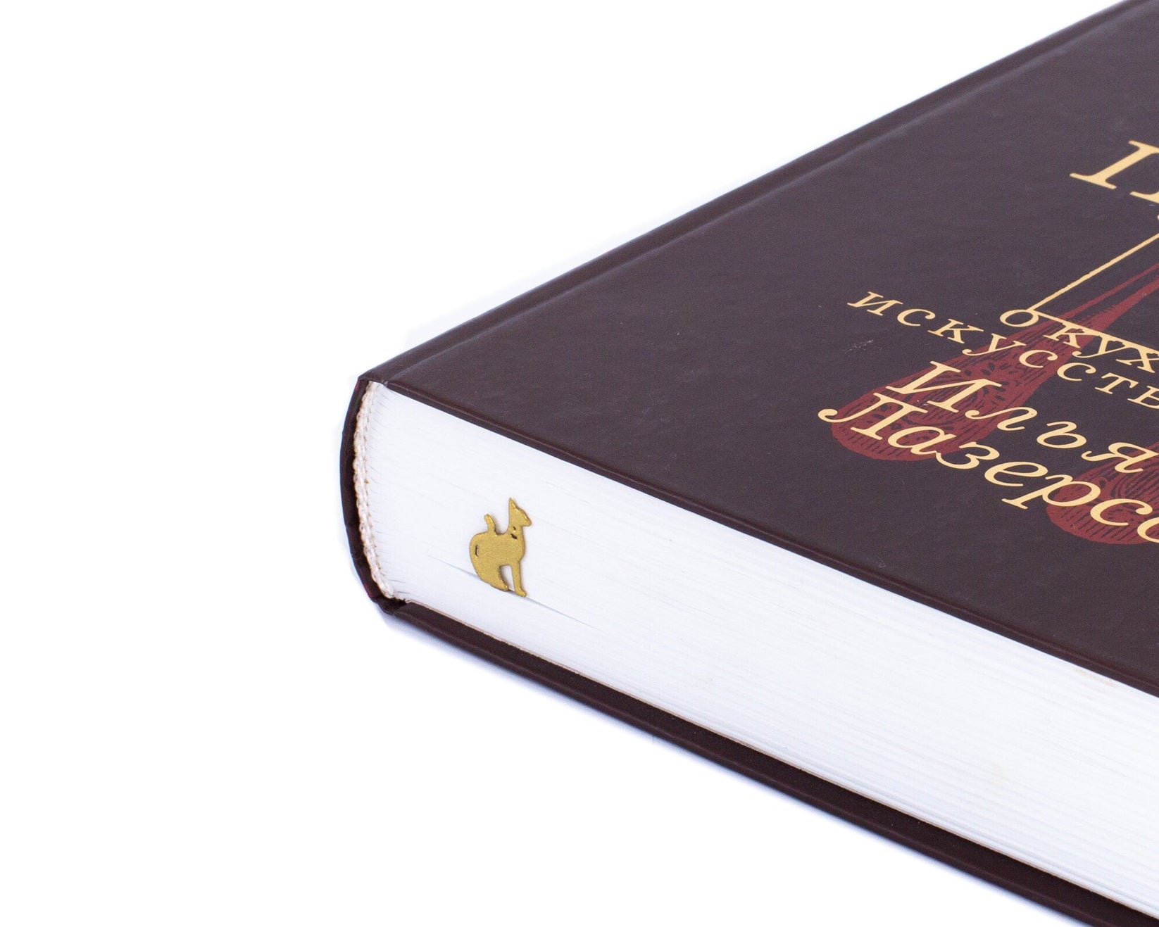 Egyptian Cat metal bookmark in gold in a closed book, only its top showing above the pages