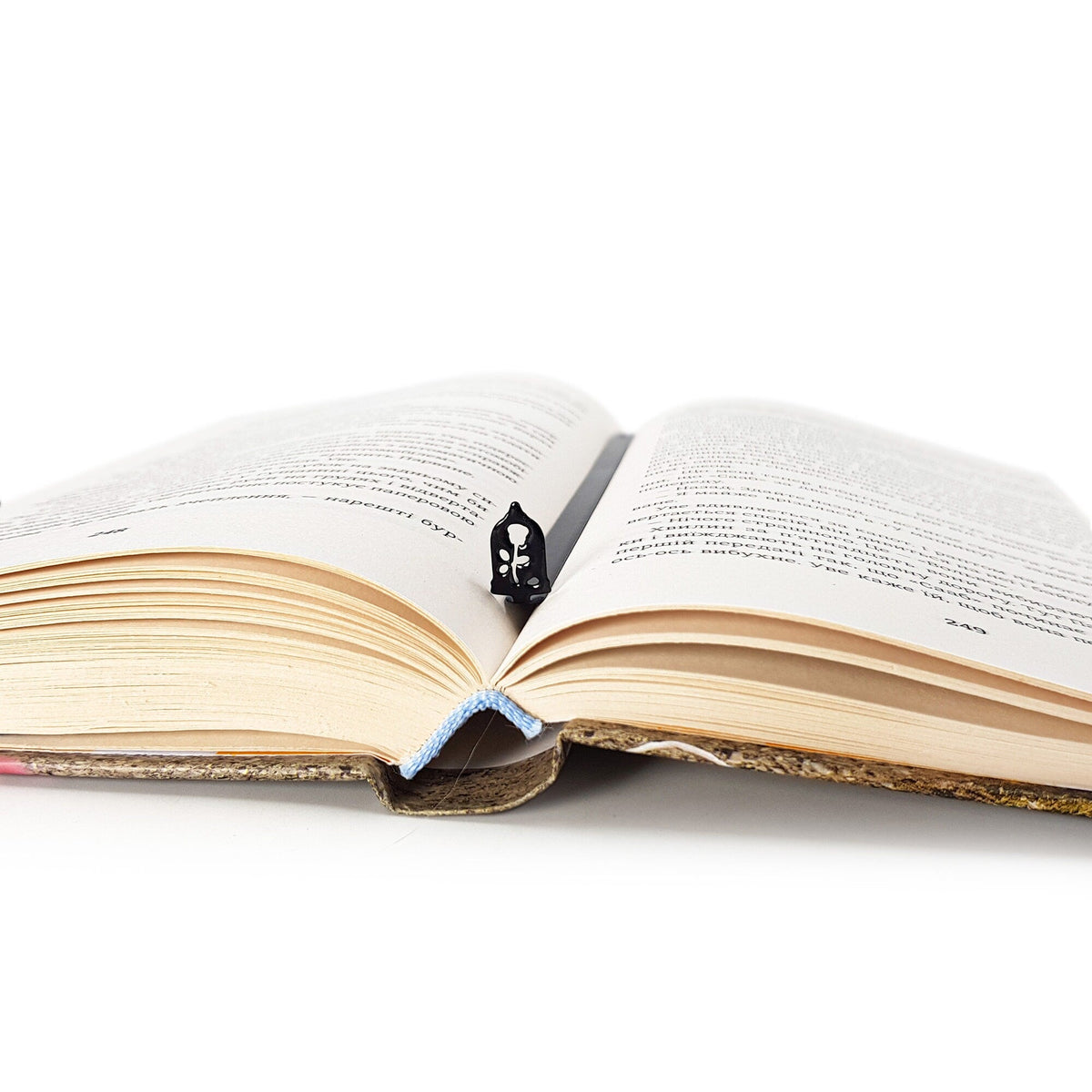 Enchanted Rose metal bookmark lying across the pages of an open book