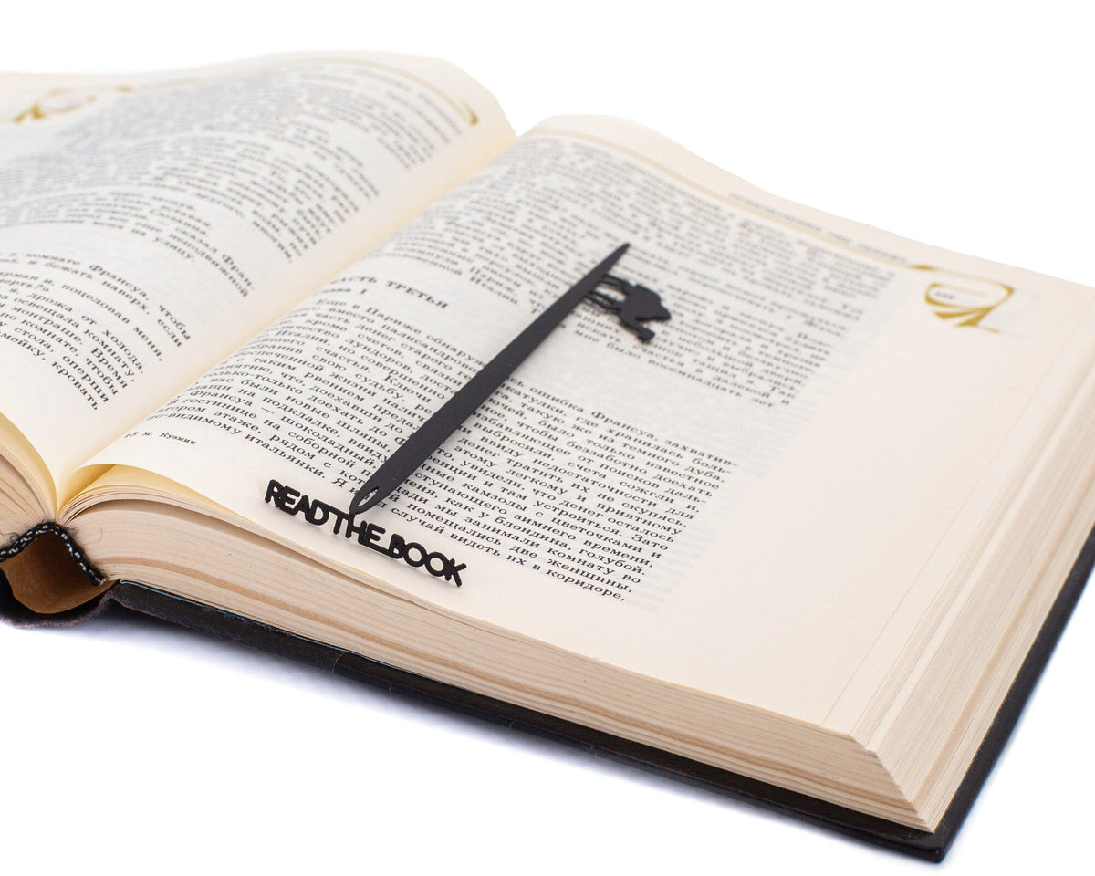 Eye of a Needle metal bookmark marking a page in an open book
