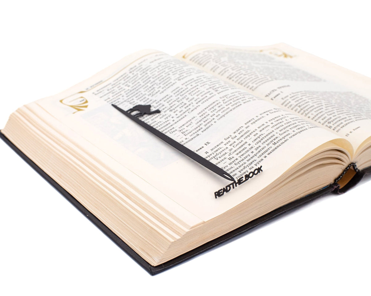 Eye of a Needle metal bookmark lying across the pages of an open book