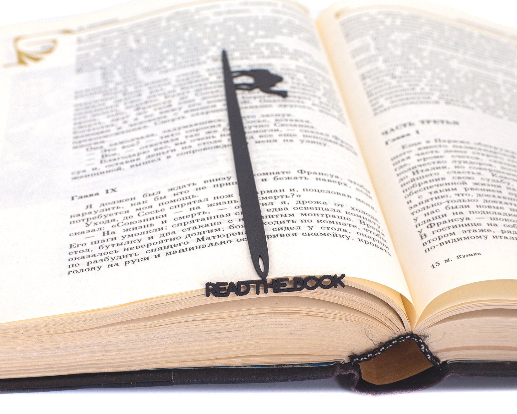 Eye of a Needle metal bookmark resting on the pages of an open book
