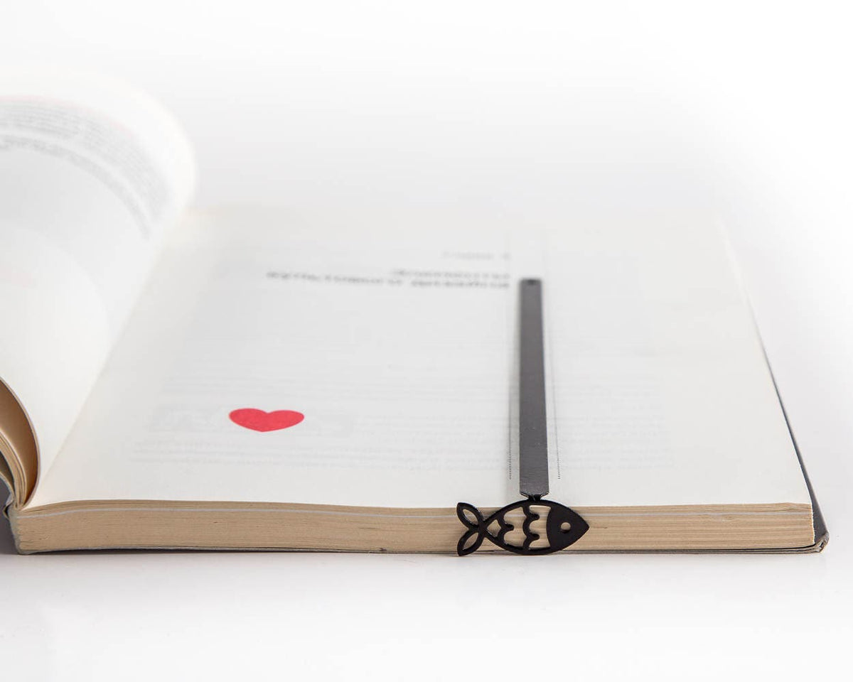 Fish metal bookmark marking a page in an open book