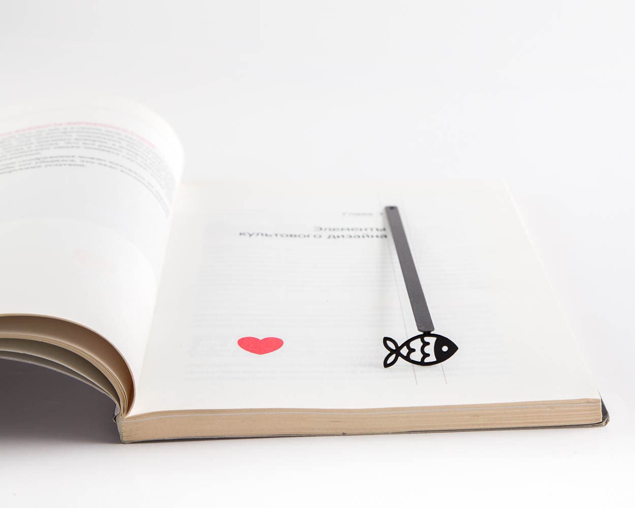 Fish metal bookmark resting on the pages of an open book