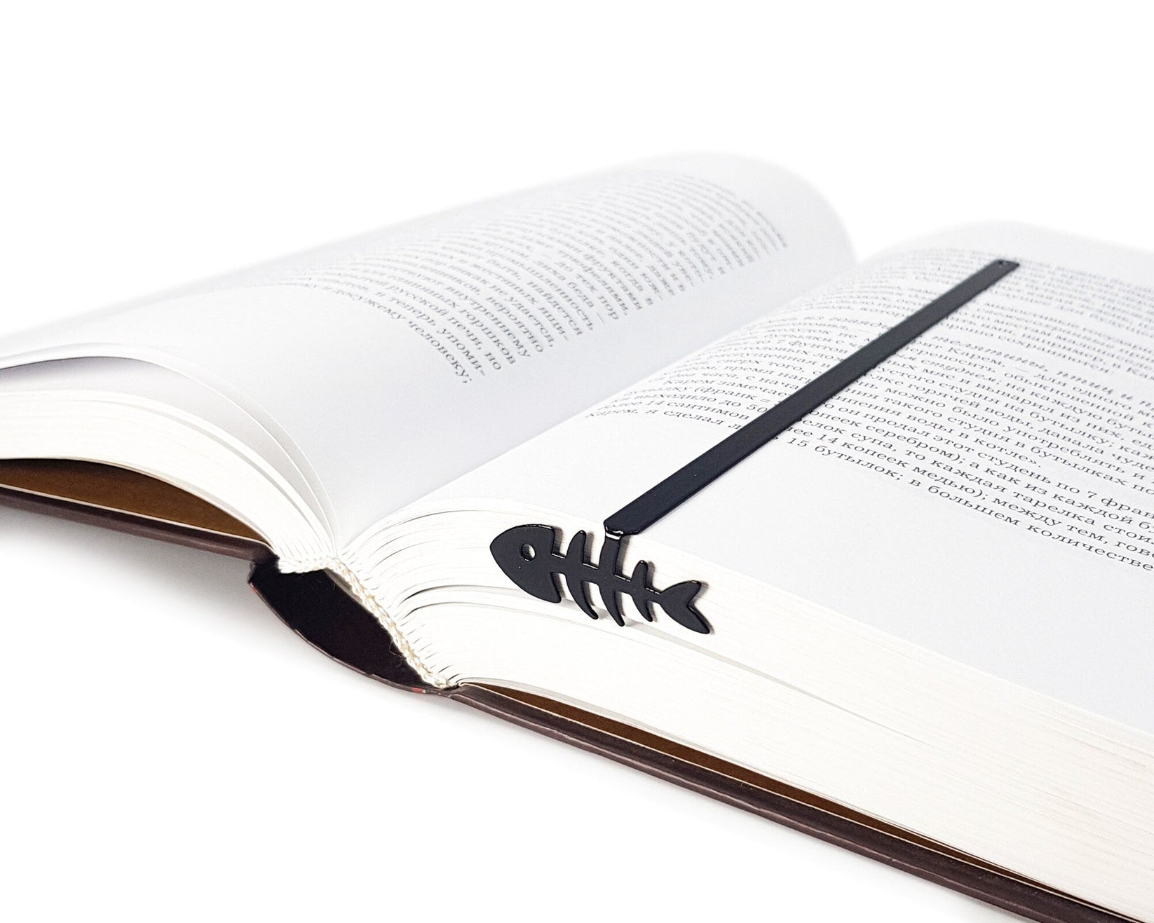 Fishbone metal bookmark marking a page in an open book