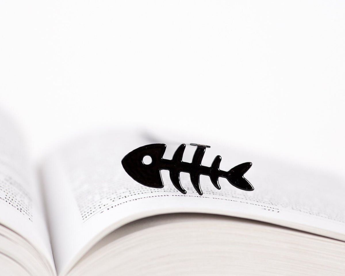 Fishbone metal bookmark resting on the pages of an open book
