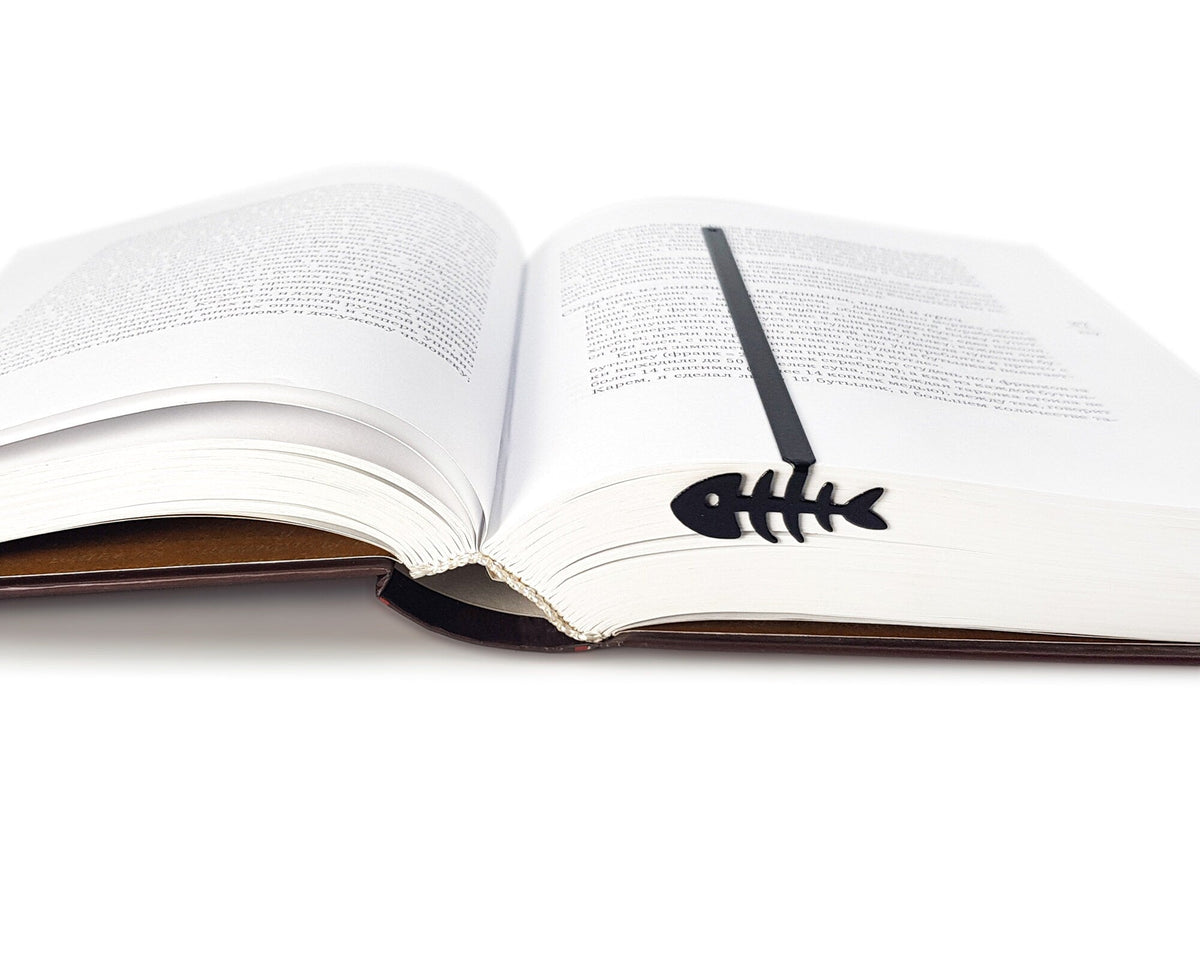 Fishbone metal bookmark resting on the pages of an open book, view 5