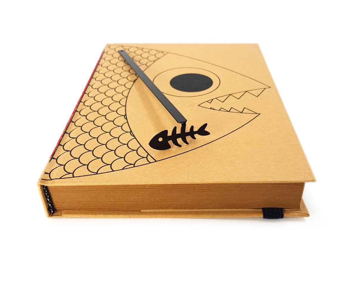 Fishbone metal bookmark in a closed book, only its top showing above the pages
