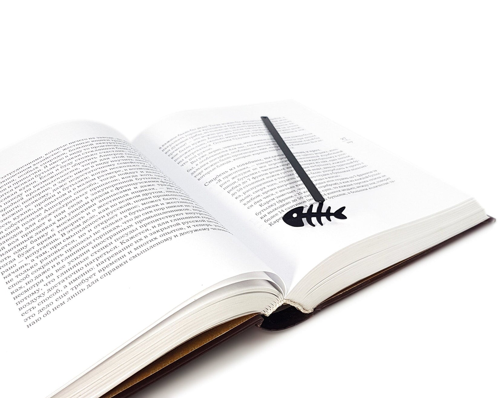 Fishbone metal bookmark lying across the pages of an open book