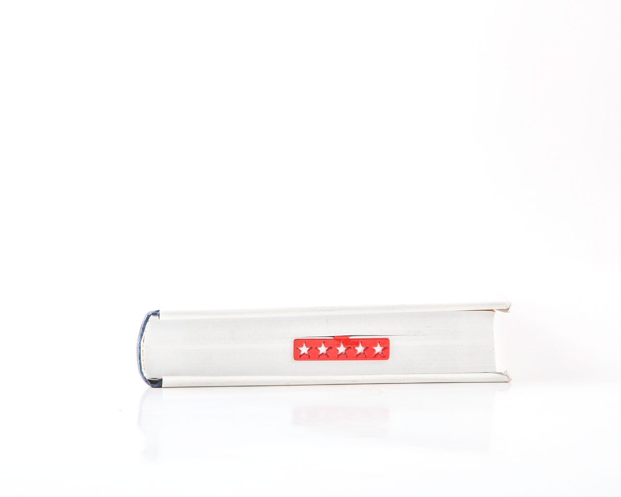 Five Star Bestseller metal bookmark in red in a closed book, only its top showing above the pages