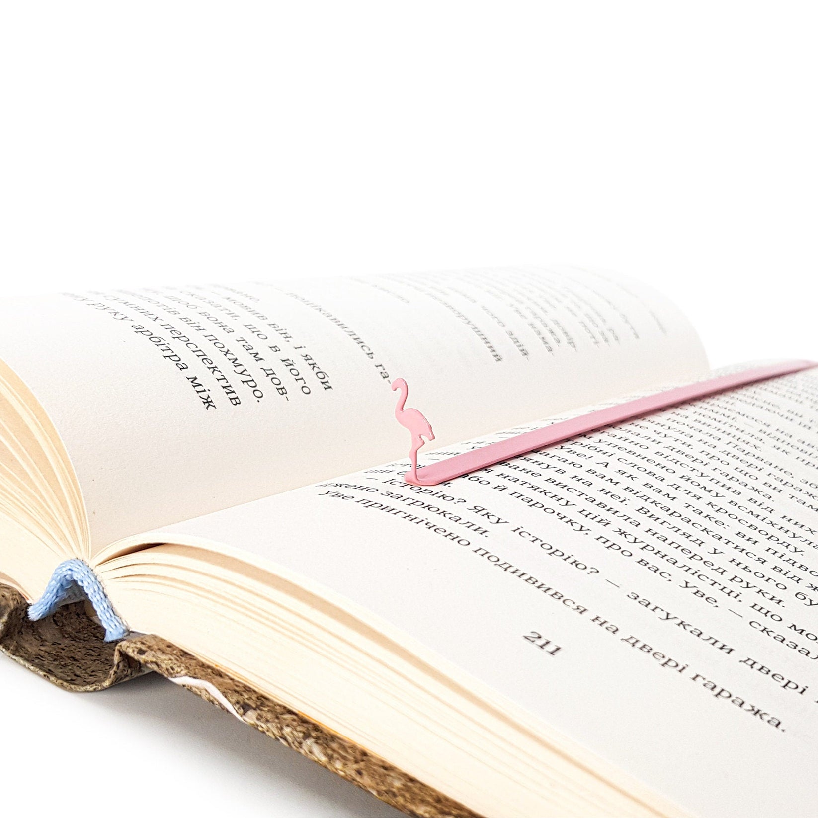 Flamingo metal bookmark in red marking a page in an open book