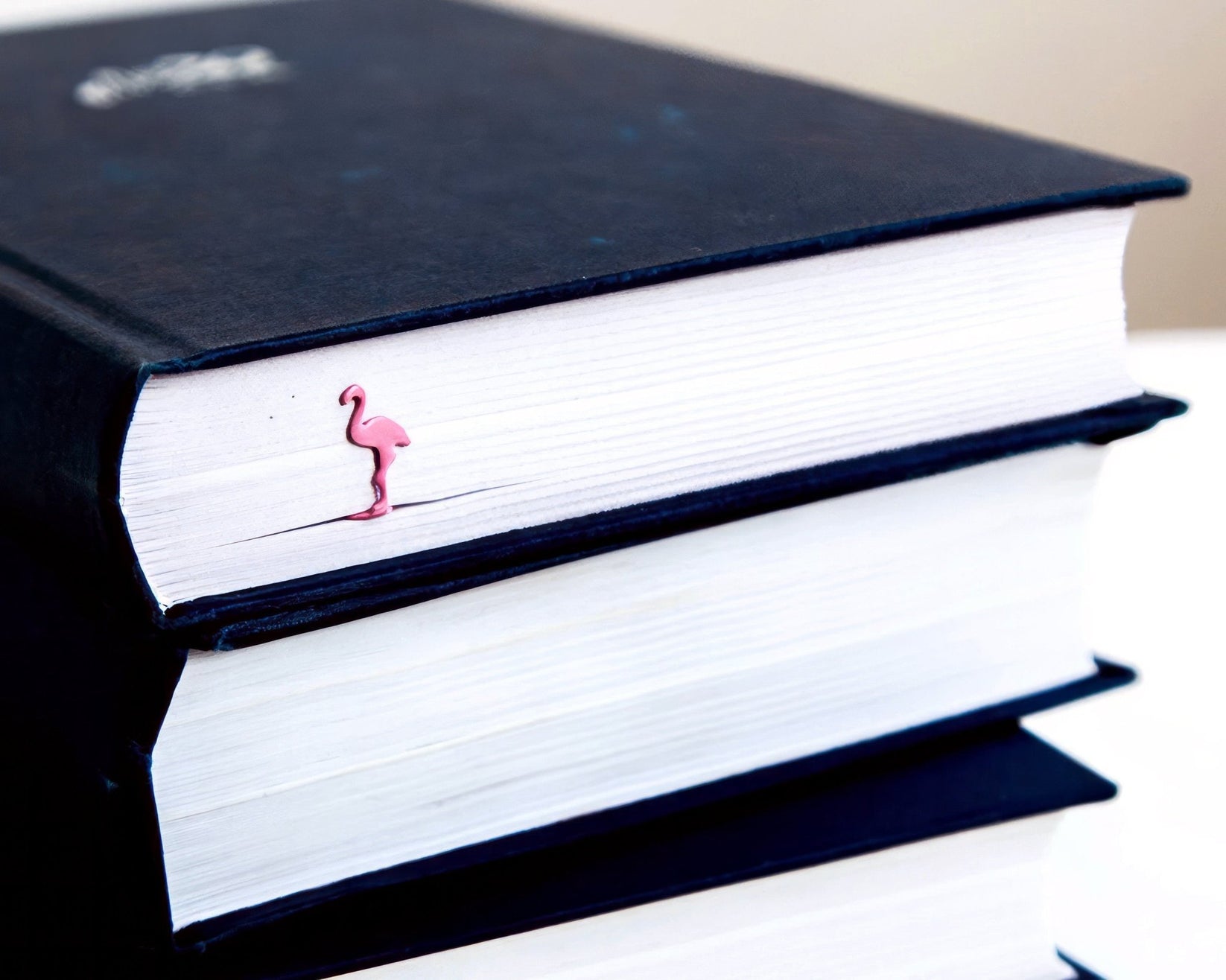 Flamingo metal bookmark in red shown with a stack of books