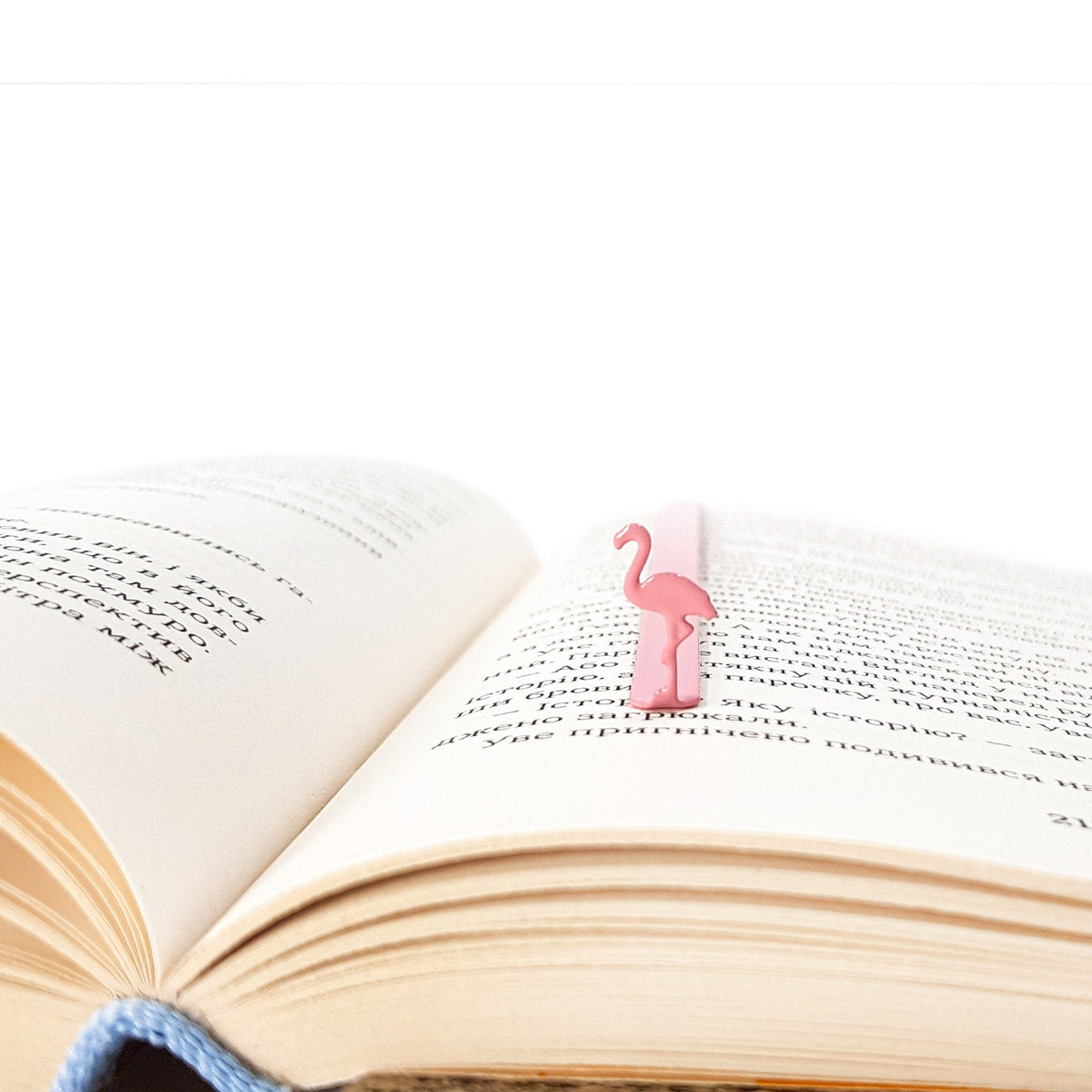 Flamingo metal bookmark in red resting on the pages of an open book