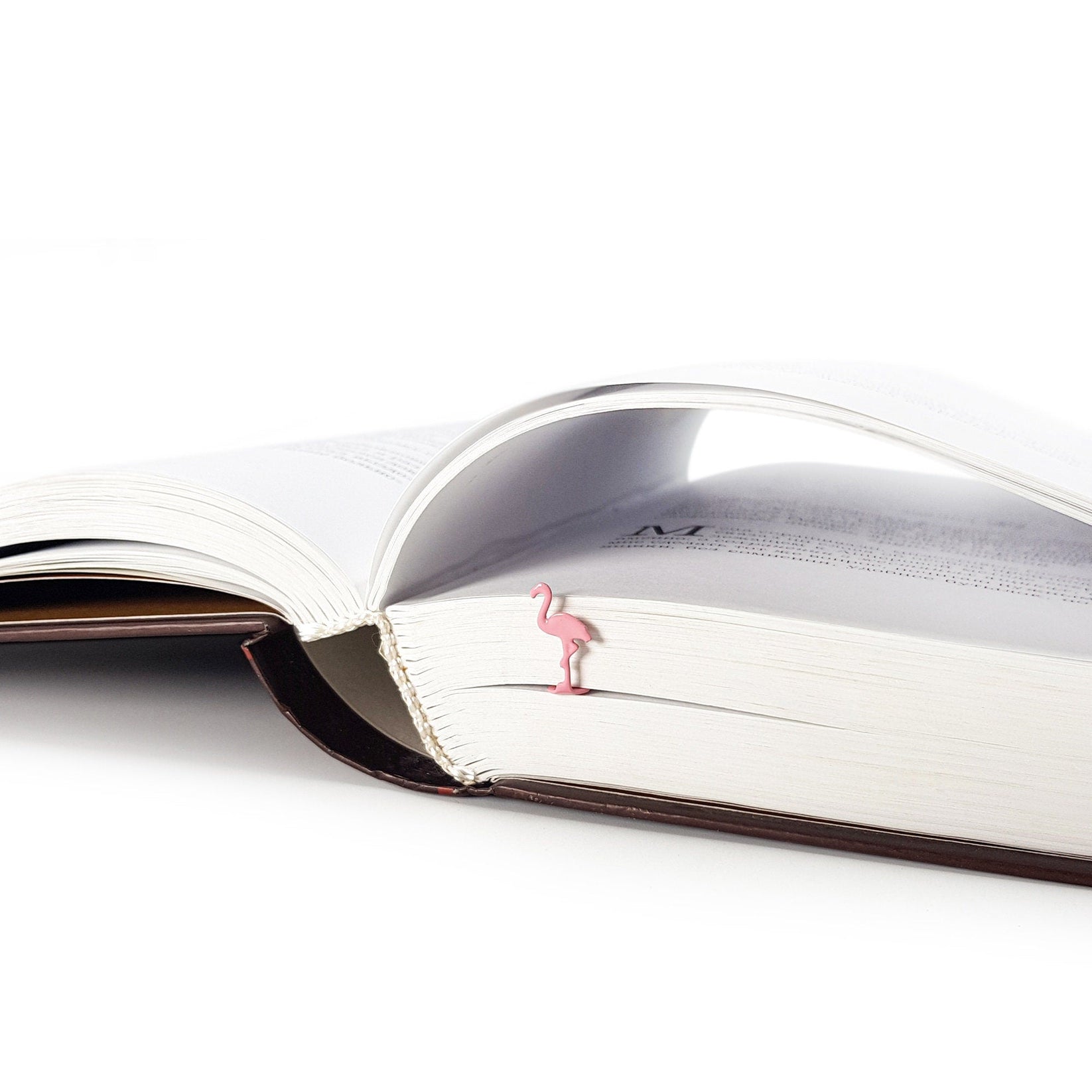 Flamingo metal bookmark in red in a closed book, only its top showing above the pages