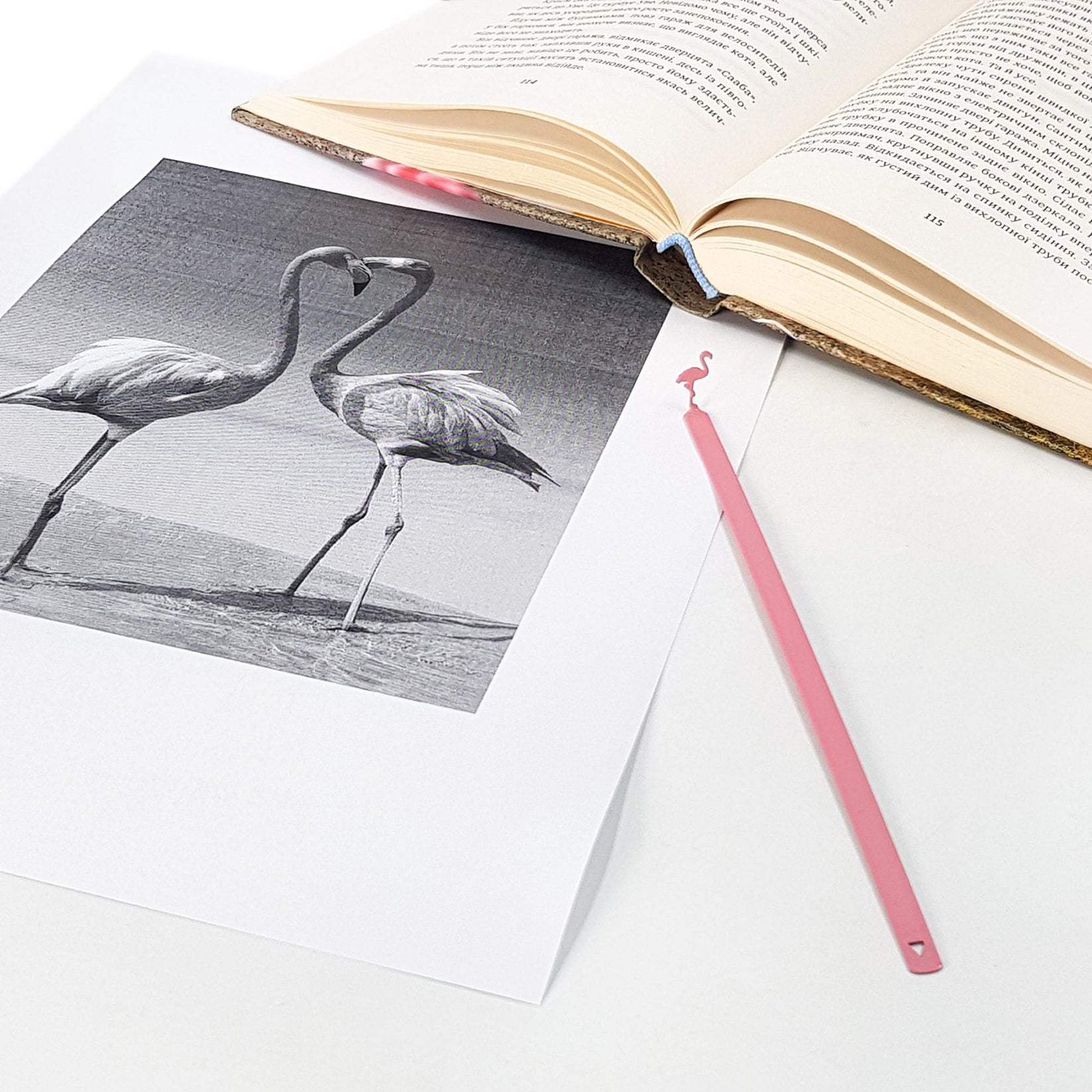 Flamingo metal bookmark in red marking a page in an illustrated book