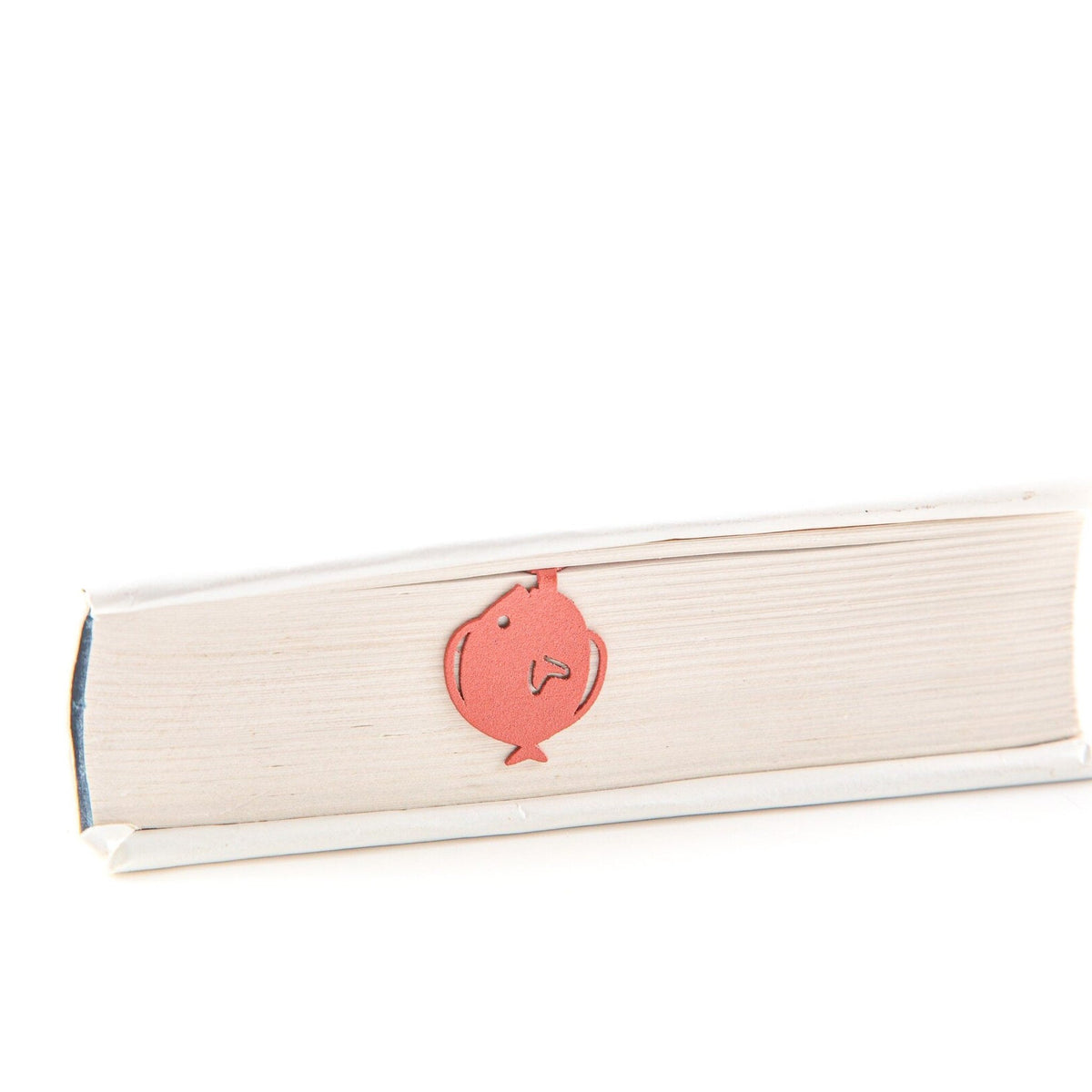 Flounder metal bookmark in red in a closed book, only its top showing above the pages
