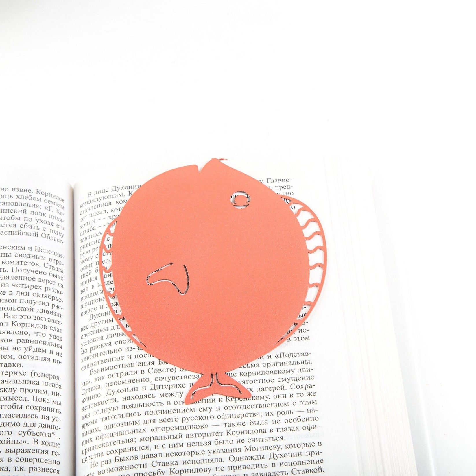 Flounder metal bookmark in red lying across the pages of an open book